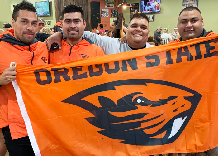 Photo of pregame meetup attendees smiling and holding an OSU flag