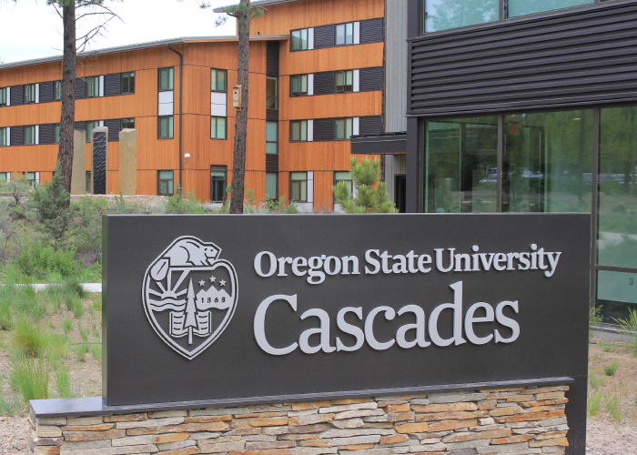 OSU-Cascades sign closeup with buildings in the background
