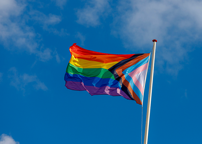Photo of a Pride Flag with blue sky behind