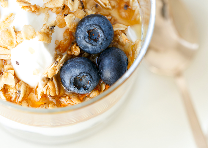 Close up photo of yogurt topped with granola and blueberries