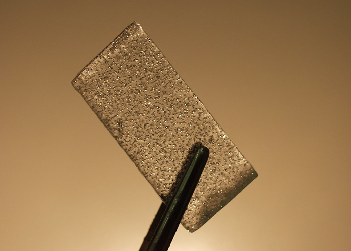 ice sample held up by large tweezers with a gold background