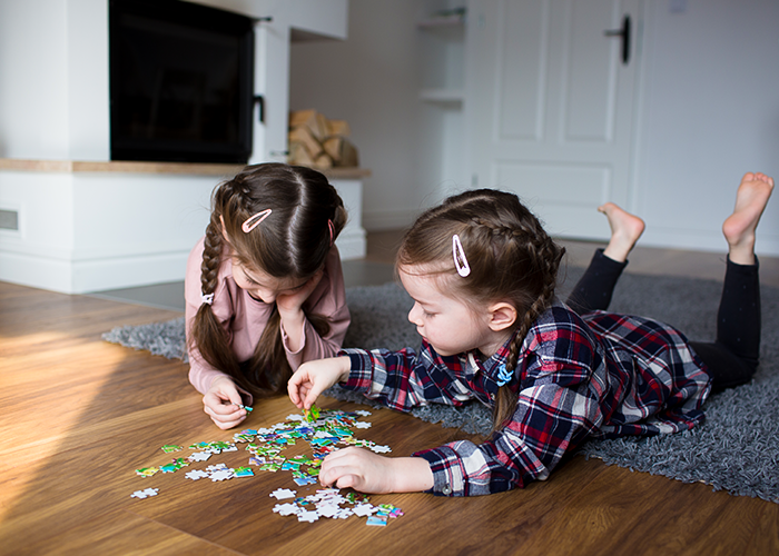 Photo of two children on floor putting puzzle together