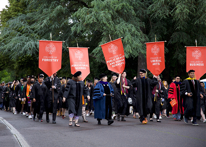 Studetns and faculty in the commencemtn procesional walking down 26th street towards Reser Stadium