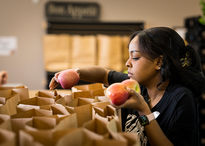 Woman packing apples in paper bags.